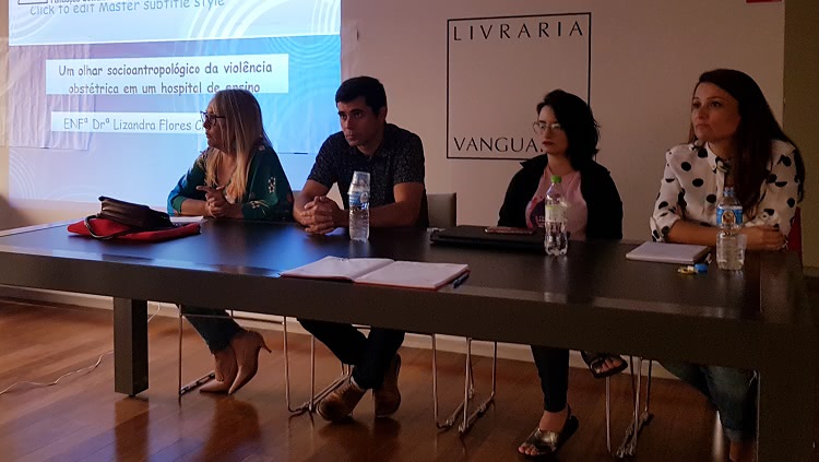 Na foto, os palestrantes estão sentados à mesa em frente a uma projeção com a apresentação na livraria Vanguarda, onde ocorreu o evento.