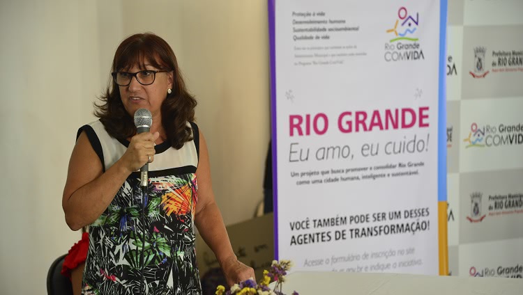 Reitora Cleuza aparece à esquerda na imagem, com o microfone na mão. À direita da foto, um banner, em que se lê o texto: Rio Grande: eu amo, eu cuido.